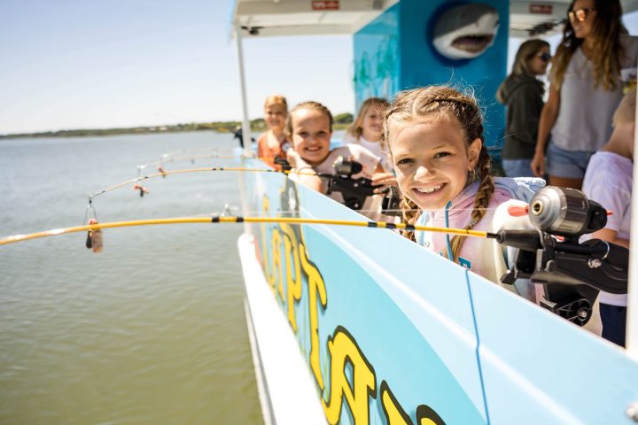a group of kids fishing on a boat